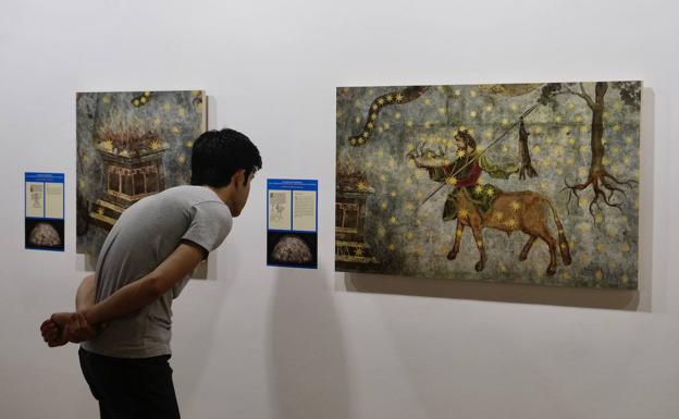 Una persona observan una obra de la exposición 'El retorno del Cielo de Salamanca. Arte y astronomía en la bóveda de la antigua biblioteca universitaria'.